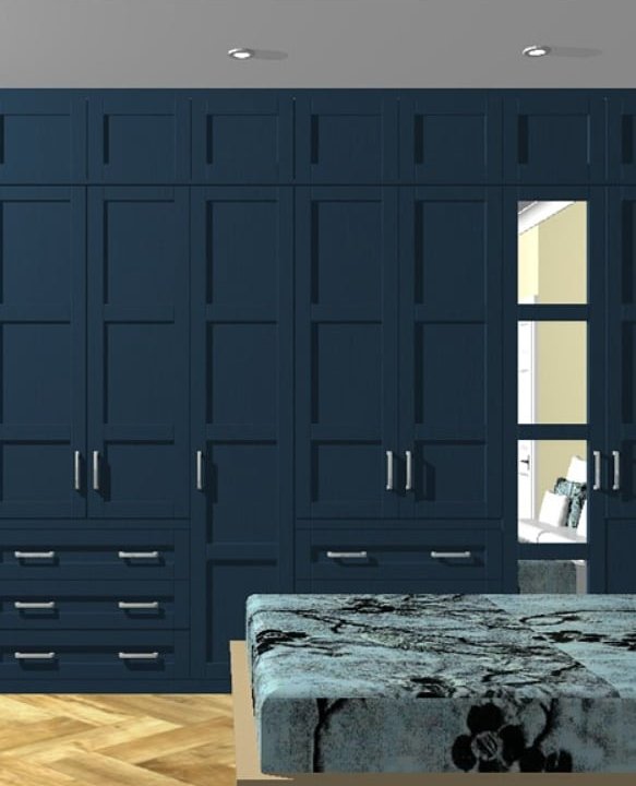 Dark blue fitted wardrobe with shaker-style doors, integrated drawers, and built-in shelving in a bedroom.