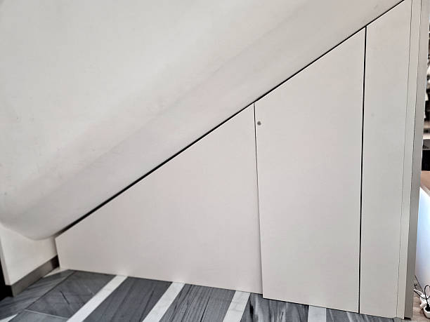 white laminate doors storage space located under the stairs. This type of furniture effectively uses the often unused triangle under the stairs. It is custom-made so that the cabinet fits exactly into